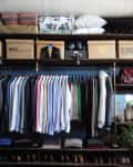 Organized closet with hanging shirts, folded clothes, shoes, and storage boxes on shelves.