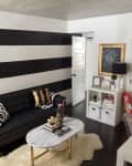 Living room with black and white striped wall, black sofa, marble coffee table, and decorative pillows.