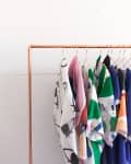 Colorful patterned fabrics hanging on a copper clothing rack.