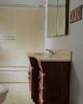 Small bathroom with a wooden vanity, beige countertop, sliding shower door, and a toilet.