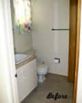 Small bathroom with beige walls, colorful curtain, white sink, and toilet.