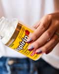 A woman holding a bottle of aspirin.