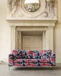 Floral patterned sofa with vibrant colors in front of ornate fireplace and mirror.