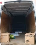 Empty van interior with two cardboard boxes labeled "medium" and a pile of green apples on the floor.