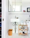 A small bathroom with tiny white tiles and a small wood shelf
