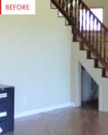 Wooden staircase with dark railing in a room with light walls and hardwood floors, next to a black filing cabinet.