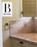 Small kitchen corner with pink marble countertop, beige shutters, and a single sink under a window.
