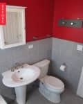 Small bathroom with red walls, white sink, toilet, and gray tile.