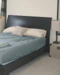 Modern bedroom with a dark wood bed frame, blue bedding, and a decorative pillow.