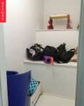 Small cluttered closet with bags, a yoga mat, and a child's stool.