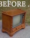 Vintage wooden console TV on a driveway with grass in the background.