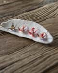 White ceramic leaf-shaped dish with small origami cranes on a rustic wooden surface.