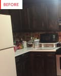 Dark wood kitchen cabinets, white countertops, stainless steel stove, and microwave with a vintage wallpaper backsplash.