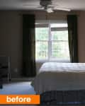 Bedroom with a large window, dark curtains, bed with pillows, and a lit table lamp on a nightstand.