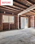 Unfinished garage with exposed wooden beams, open door, and paint cans.