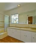 Bathroom with a shower-tub combo, white cabinets, beige countertop, and a window with decorative glass.