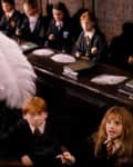 Students in robes practicing levitation with feathers in a classroom.