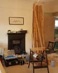 Living room under renovation with tools, wooden planks, and a fireplace.