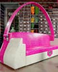 Pink and white crocodile-patterned sofa with a large arch, surrounded by shelves of colorful decor items.