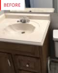 Bathroom with beige sink, wooden vanity, and white toilet under a large mirror.
