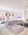 Spacious living room with a large gray sectional, fluffy rug, hanging swing, and modern chandelier.
