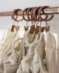 Copper curtain rod with rings holding beige fabric with tassels.