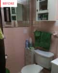 Small bathroom with pink tiles, white toilet, green towels, and a mirrored cabinet above the sink.