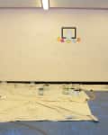 Empty room with paint cans on drop cloths, a basketball hoop, and a "Before" label on the wall.
