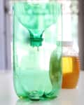 Green plastic bottle trap with liquid inside, next to a jar of honey.