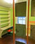 Small room with green walls, built-in shelves, a desk, and a chair. Hanging panels divide the space.