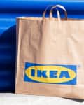 Brown paper bag with IKEA logo against a blue corrugated metal wall.