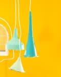 Three colorful pendant lamps in turquoise and mint green against a vibrant yellow wall, with a white birdcage in the background.