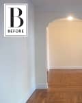 Empty room with light-colored walls, arched doorway, and wooden parquet flooring.
