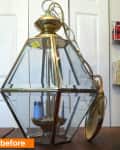 Brass and glass hexagonal pendant light with chain on wooden table.