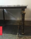 Marble-topped table with ornate brass legs on a slate tile floor.