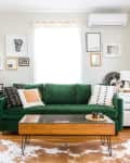 Green velvet sofa with patterned cushions, wooden coffee table, and wall art in a bright living room.