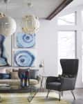 Modern living room with abstract art, gray chairs, glass coffee table, and pendant lights.