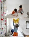 Children playing on a cloud-shaped loft bed in a floral-decorated room.
