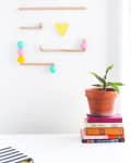 Wooden wall hanging with colorful balls and heart, next to a potted plant on stacked books.