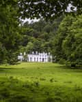 White castle with arched windows surrounded by lush green trees and grass.
