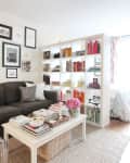 A large white bookshelf separating a bedroom from a living space in a studio apartment