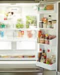 Open refrigerator with various condiments, drinks, and fresh produce on shelves and door compartments.