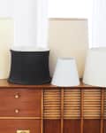 Assorted lamp shades in various shapes and colors on a wooden dresser.