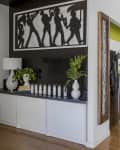Open-concept kitchen and dining area with green accent wall, plants, and a person working at a wooden table.