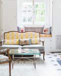 Elegant living room with vintage sofa, glass coffee table, patterned cushions, and a fireplace.