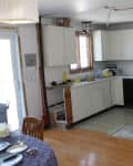 Kitchen with white cabinets, stainless steel stove, cluttered countertops, and cleaning tools on the floor.