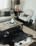 Living room with a gray sofa, patterned pillows, wooden coffee table, cowhide rug, and a cozy armchair.