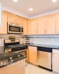 Modern kitchen with light wood cabinets, black countertops, stainless steel appliances, and subway tile backsplash.