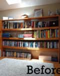 Wooden bookshelves filled with books and DVDs in a cozy room with a white rug.
