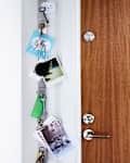 Keys and photos hanging on a magnetic strip next to a wooden door with a silver handle.